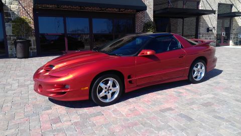 1980 Pontiac Trans Am - This red Pontiac Firebird is parked outside a building with large glass windows.