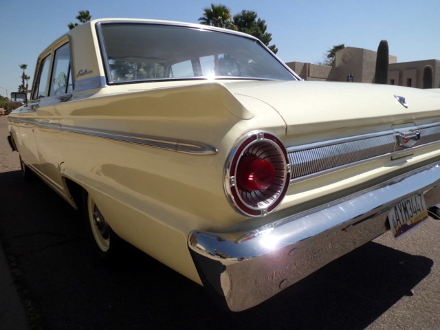 Rear quarter view of a yellow 1963 Ford Falcon sedan. It has a chrome bumper and a round taillight