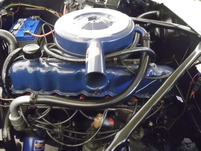 Close-up of a blue engine with a round air filter and battery