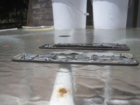 1993 Ford Bronco - Two old car emblems are shown on a glass table, possibly for a 1993 Ford Bronco.
