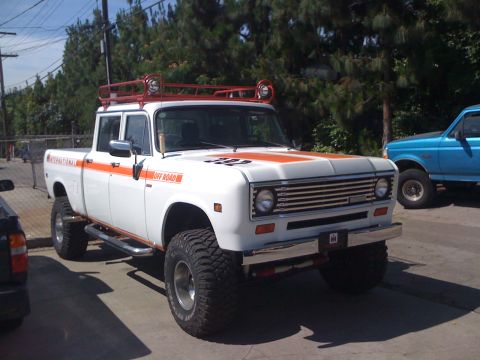 1968 Ford Mustang - Modified International Harvester pickup truck with off-road tires and roof rack. Another truck is visible to the right.