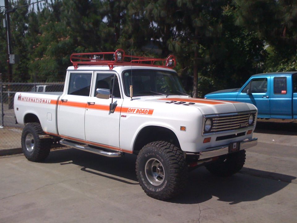 White International pickup truck with orange stripes, roof rack, and off-road tires