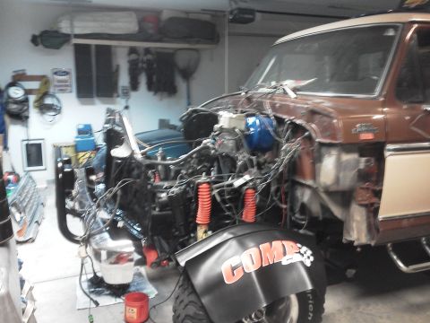 1979 Ford F-150 - The front end of a 1979 Ford F-150 is disassembled in a garage, revealing the engine and wiring components.