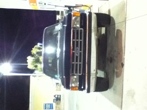 1988 Ford Bronco - This Ford Bronco is at a gas station, possibly refueling. The grille and headlights are visible.