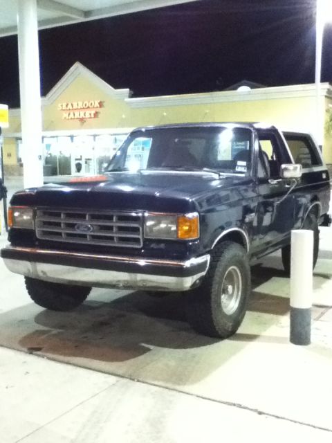 1988 Ford Bronco - A dark blue Ford Bronco is parked at a gas station in front of a market.