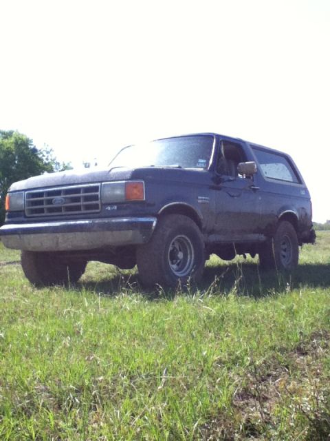 1988 Ford Bronco - This Ford Bronco is parked in a grassy field under a clear sky.