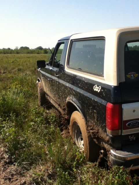 1988 Ford Bronco - This 1988 Ford Bronco is stuck in the mud off-road, with its tires sunk deep into the wet ground.