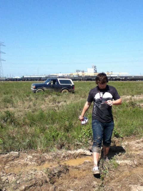 1988 Ford Bronco - A person walks through a muddy field towards a dark blue Ford Bronco.