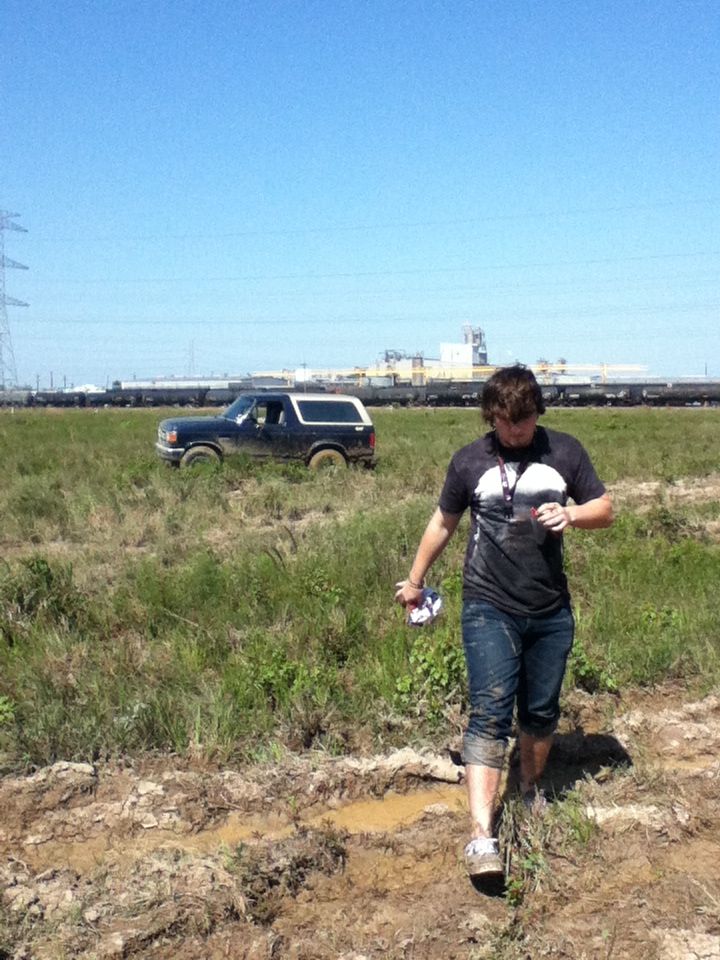 Dark blue Ford Bronco with a white top parked in a muddy field