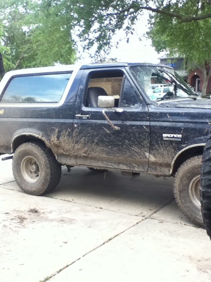 Side view of a mud-splattered 1988 Ford Bronco with a white top