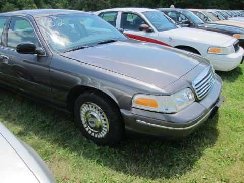 2001 Ford Crown Victoria - A row of Ford Crown Victorias are parked on a grassy field, with one in the foreground showing its front passenger side.