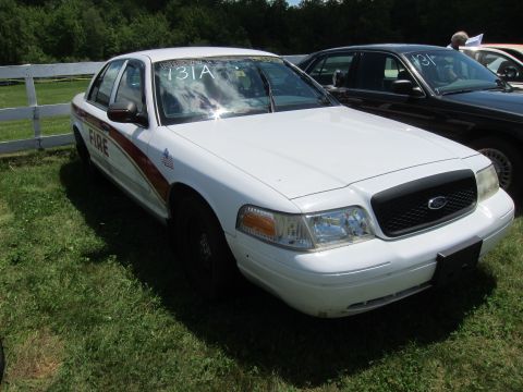 2001 Ford Crown Victoria - White 2001 Ford Crown Victoria, marked with 'FIRE' text, seen at an outdoor event with other vehicles present.