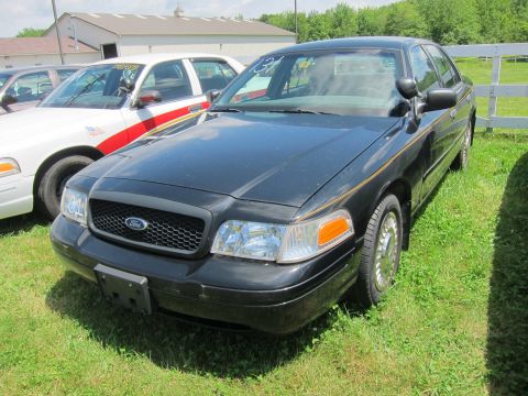 2001 Ford Crown Victoria - A black 2001 Ford Crown Victoria is parked on grass next to other vehicles.