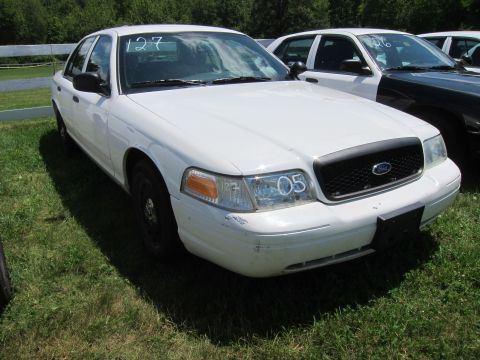2001 Ford Crown Victoria - A white sedan, possibly a police car, is parked outdoors. The number '05' is visible on the headlight assembly.