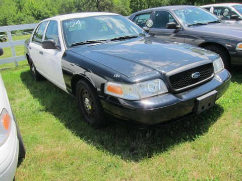 2001 Ford Crown Victoria - A black and white Ford Crown Victoria is parked on a grassy lot next to another vehicle.