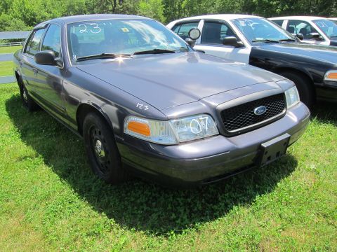 2001 Ford Crown Victoria - This dark gray sedan is seen from the front quarter angle, with '07' visible on the headlight.