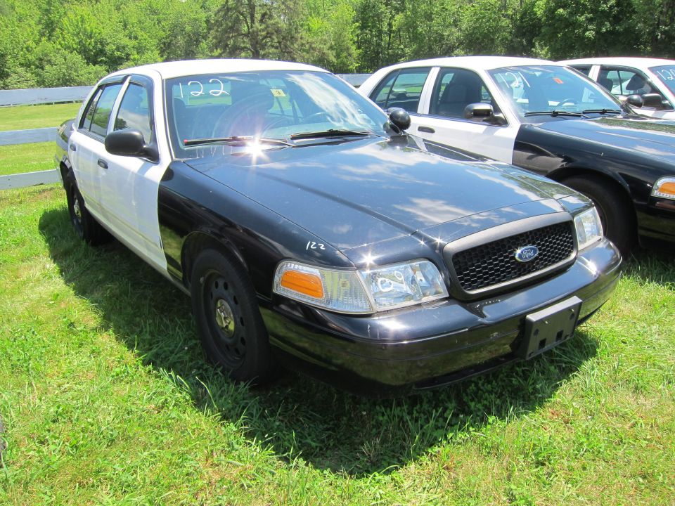 Black and white police car parked on grass, another police car behind it
