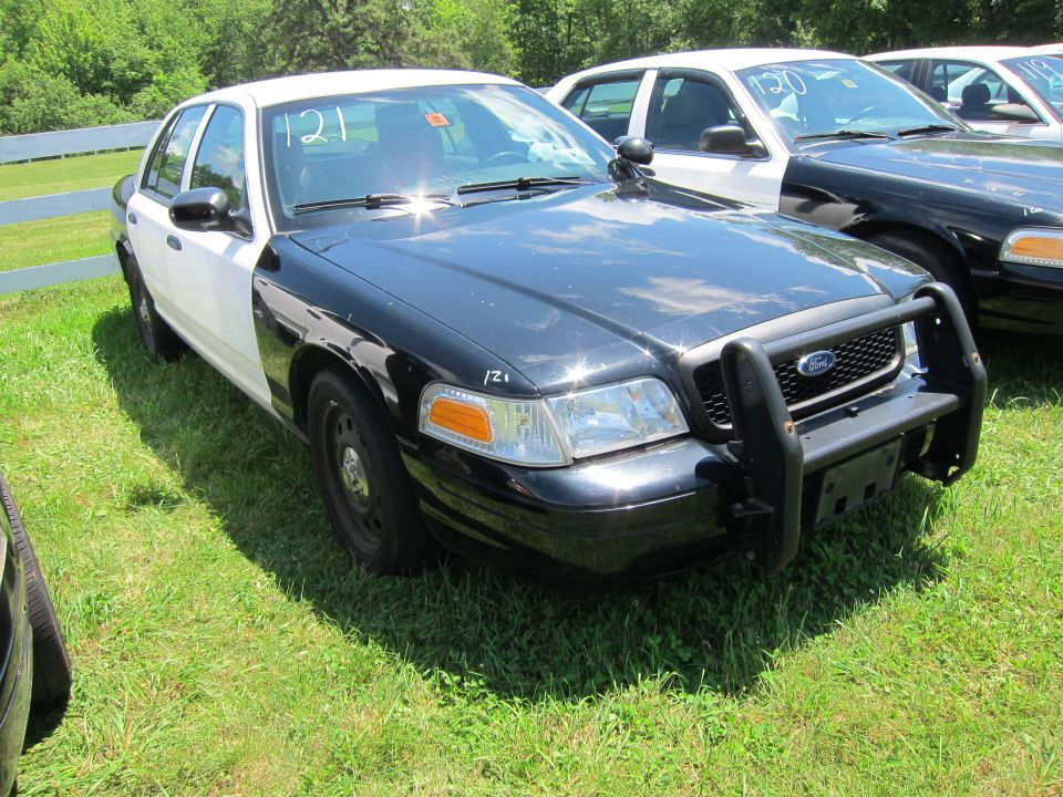 Black and white police car with push bumper, parked on grass