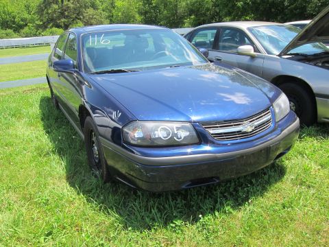 2001 Ford Crown Victoria - A blue sedan is parked on a grassy area with another vehicle visible to its right.