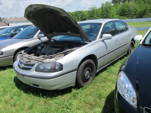 2001 Ford Crown Victoria - A silver sedan is parked on a grassy area with its hood open, revealing the engine compartment.