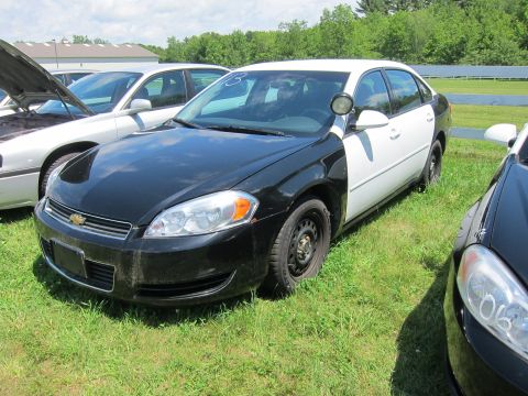 2001 Ford Crown Victoria - A black and white police car is parked on grass next to other vehicles. The Chevrolet badge is visible on the front grille.