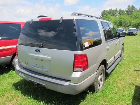 2001 Ford Crown Victoria - Rear view of a silver Ford Expedition parked on a grassy field with trees in the background.