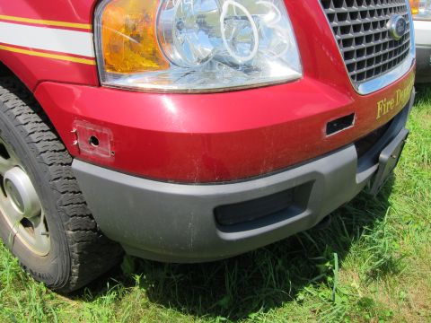 2001 Ford Crown Victoria - A red truck's front end is visible, showing a gray bumper and part of a headlight.