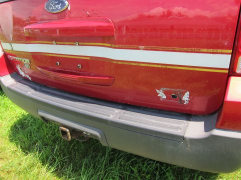2001 Ford Crown Victoria - Rear view of a red Ford Expedition, showing the tailgate, tow hitch, and distinctive stripe.