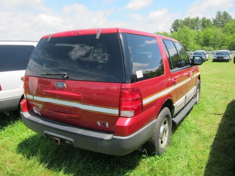 2001 Ford Crown Victoria - Rear view of a red Ford Expedition SUV with reflective stripes, parked on grass.