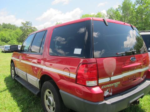 2001 Ford Crown Victoria - A red Ford Expedition SUV is parked on grass, showing its rear and side with emergency service markings.