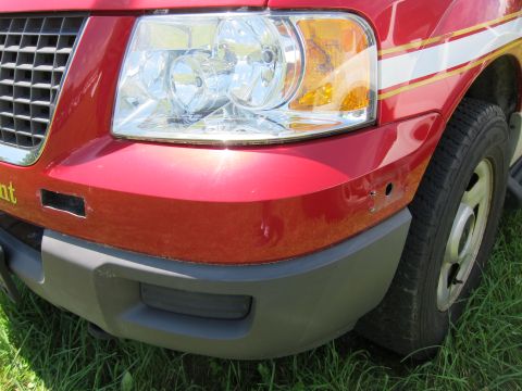 2001 Ford Crown Victoria - Front corner of a red truck, possibly a Ford F-150, showing the headlight, grille, and bumper detail.