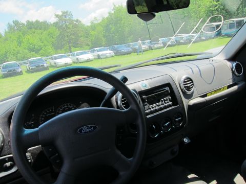 2001 Ford Crown Victoria - View from inside a Ford, showing the dashboard and a line of cars parked on a grassy field.