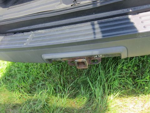 2001 Ford Crown Victoria - Close-up of a vehicle's rear bumper and a rusty trailer hitch, set against a grassy background.