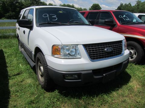 2001 Ford Crown Victoria - White Ford Expedition with '93' written on windshield parked next to a red vehicle.