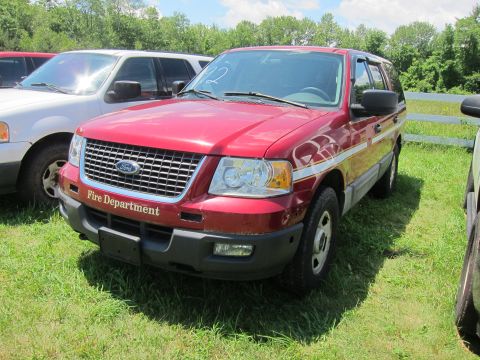 2001 Ford Crown Victoria - This red Ford Expedition, marked "Fire Department", is parked outdoors next to other vehicles.