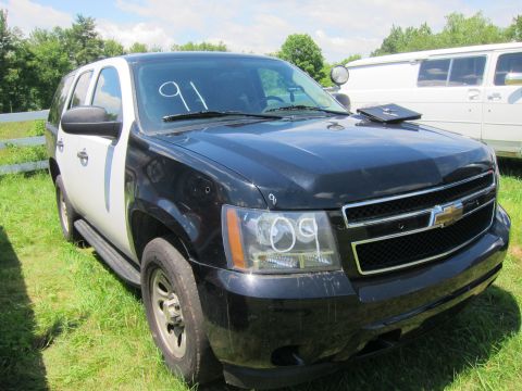 2001 Ford Crown Victoria - A black and white police SUV is parked in a grassy area next to a white van. The number '91' is written on the windshield.