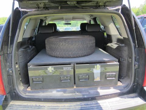 2001 Ford Crown Victoria - Spare tire and storage boxes are loaded in the cargo area of a black SUV.
