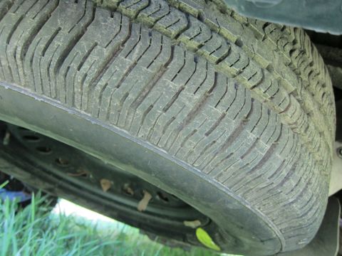 2001 Ford Crown Victoria - A spare tire is shown, with its tread and rim clearly visible. Some debris is caught around the wheel.