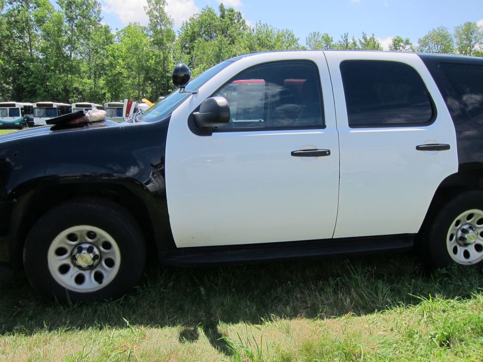 Side view of a black and white police SUV with a light bar on the roof