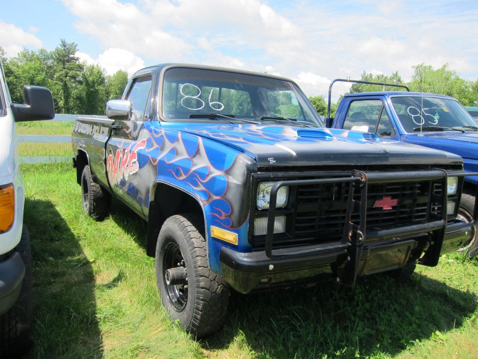 Blue pickup truck with flame graphics and a black grille guard parked next to a blue truck
