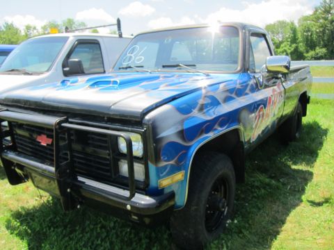 2001 Ford Crown Victoria - A customized pickup truck with flame graphics and a bull bar is parked next to a white van on a sunny day.