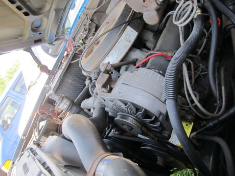 2001 Ford Crown Victoria - The engine bay of a vehicle is shown, with various components and a glimpse of another vehicle through the radiator.