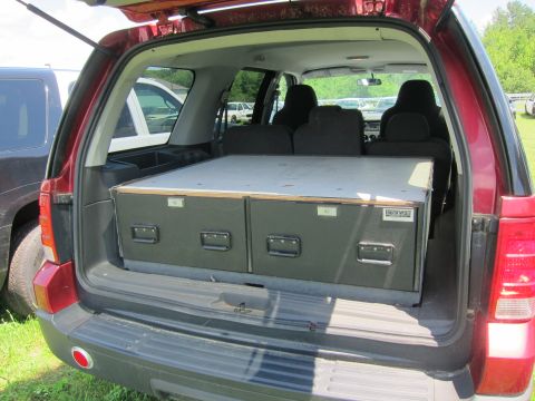 2001 Ford Crown Victoria - The rear of a red SUV is open, revealing two dark grey storage drawers with metal handles.