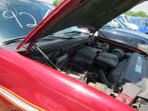 2001 Ford Crown Victoria - The engine compartment of a red vehicle is shown with the hood raised, revealing the engine and other components.