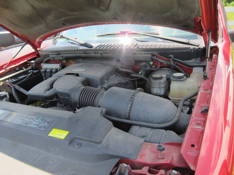 Engine bay of a red vehicle, showing the air intake and various fluid reservoirs