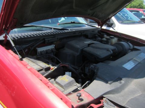 2001 Ford Crown Victoria - The engine bay of a red vehicle is visible with the hood raised, and another vehicle is parked behind it.