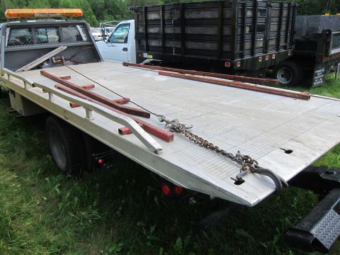 2001 Ford Crown Victoria - A tow truck's flatbed is equipped with chains and metal bars, with other vehicles visible in the background.