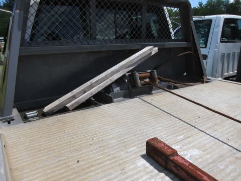 2001 Ford Crown Victoria - The bed of a tow truck features a winch and cable, with wooden ramps positioned over the winch mechanism.
