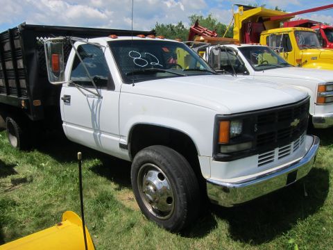 2001 Ford Crown Victoria - A white dump truck is parked on a grassy lot with other vehicles visible in the background.