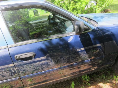 2001 Ford Crown Victoria - Side view of a blue 2001 Ford Crown Victoria showing dirt and reflections on the body panels.